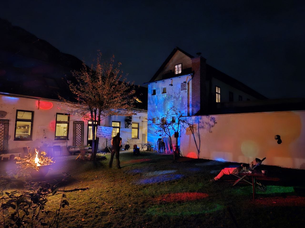 Commons Hub courtyard animated with projections and a fire at night
